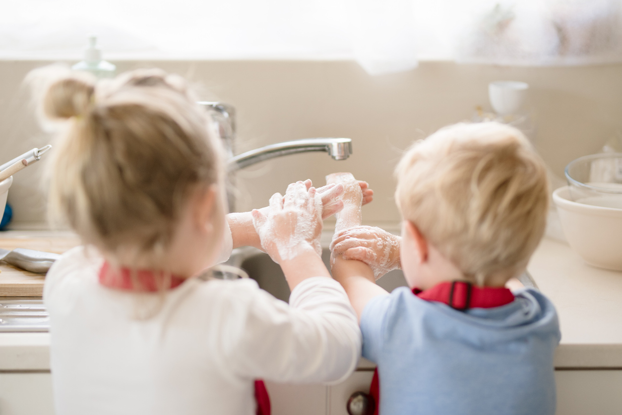 Siblings washing their hands with soap